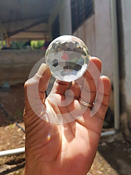 Handholding a crystal ball on blurred nature background