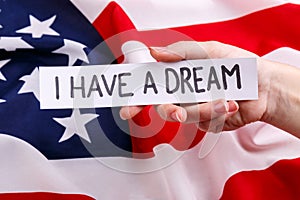 The handholds a piece of paper with the inscription Martin Luther King Jr. Day. The background of the American flag.