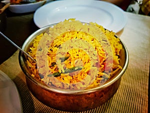 Handi biryni sweet pulao rice dish indian cuisine in a bowl on a table with white plates