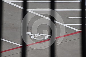 Handicap parking sign on the road through grill, handicap spot, white sign on grey asphalt