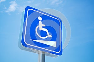 Handicap sign. White symbol over blue background on blue sky background