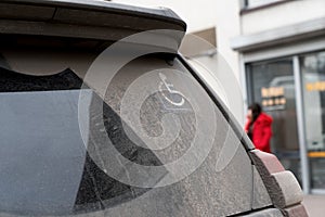 Handicap sign on the window of a black car.