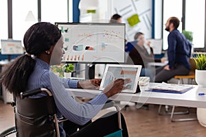 Handicapped african american businesswoman in wheelchair analyzing financial graph