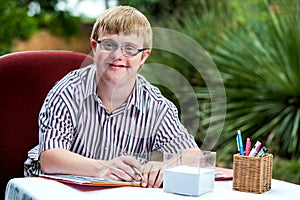 Handicapped boy at desk in garden.