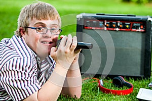Handicapped boy singing with microphone and amplifier.