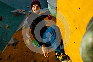 handicapped climber moving up on steep rock, climbing on artificial wall indoors