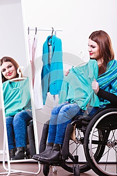 Handicapped girl on wheelchair choosing clothes