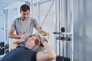 Handicapped man stretches strap on strength-training machine