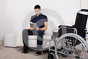 Handicapped Man Using Digital Tablet On Sofa