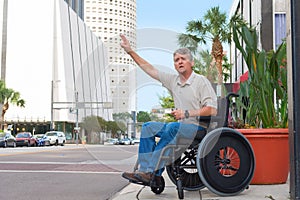 Handicapped man in a wheelchair hailing a taxi in the city