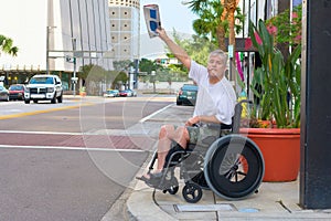 Handicapped man in a wheelchair hailing a taxi waving newspaper