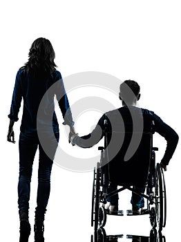 Handicapped man in wheelchair and woman holding hands silhouett