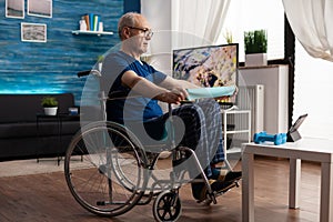 Handicapped old man in wheelchair training arm resistance exercising body muscle