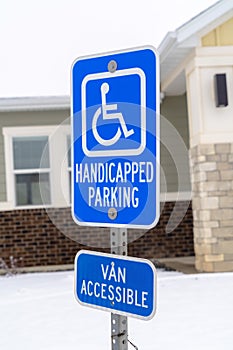 Handicapped Parking and Van Accessible sign against snow and building in winter