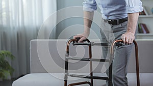 Handicapped person trying to move with walking frame at hospital, rehabilitation