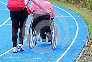 handicapped person on a wheelchair with an aide on the athletic