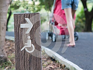 Handicapped sign in park with blurry mother push stroller along pathway