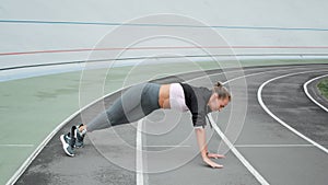 Handicapped woman doing plank on hand at stadium.Lady exercising on sports track