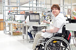 handicapped worker in a wheelchair assembling electronic components in a modern factory at the workplace