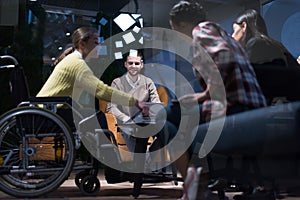 Handicapped young woman with colleagues working in office. She is smiling and passionate about the workflow. Performing in co-