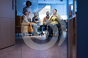 Handicapped young woman with colleagues working in office. She is smiling and passionate about the workflow. Performing in co-