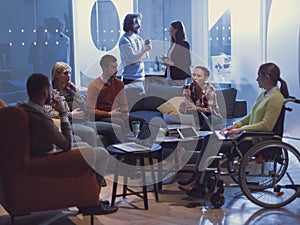 Handicapperd businesswoman in a wheelchair on meeting with her diverse business team brainstorming at office