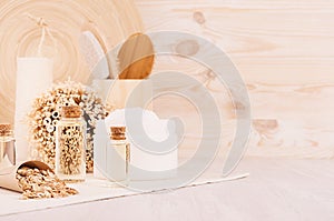 Handicraft natural cosmetics - white cream, oil, towel and bath accessories on soft light beige wood table, copy space.