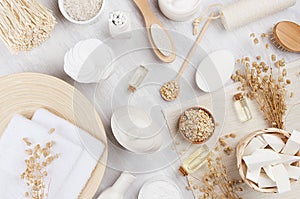 Handicraft natural cosmetics - white cream, oil, towel and bath accessories on soft light white wood table, flat lay.