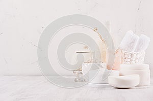 Handicraft natural cosmetics - white cream, soap, clay, towel, pink salt and bath accessories on soft light white wood table.
