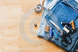 Handicraft, repair and tailoring. Sewing accessories threads close-up denim wooden table. Horizontal frame copy space