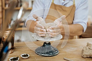 Handicraftsman forming vase with his hands on pottery wheel