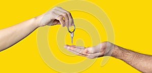 Handing keys to someone else on yellow background