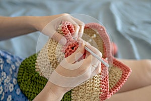 Handiwork. Knitting. Handmade. A girl crochets a colored bag