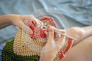 Handiwork. Knitting. Handmade. A girl crochets a colored bag