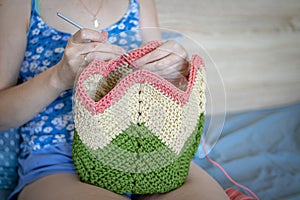 Handiwork. Knitting. Handmade. A girl crochets a colored bag