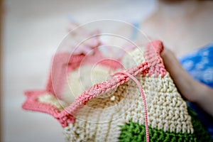 Handiwork. Knitting. Handmade. A girl crochets a colored bag