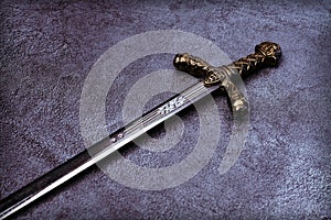 The handle of a knight`s sword on a gray background.