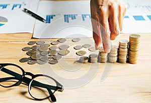 Handles coins placed on a pile of money on the table with light Sunset`s business concept