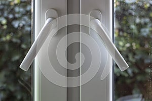 Handles on PVC structures are at an angle and the windows are not completely closed, with dusty glass through which you can see