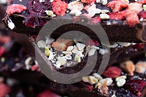 Handmade bitter chocolate with berries and green pistachios on a cork wood background. Macro photography of food. A close-up of a