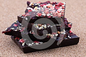 Handmade bitter chocolate with berries and green pistachios on a cork wood background. Macro photography of food. A close-up of a