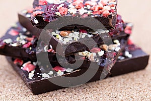 Handmade bitter chocolate with berries and green pistachios on a cork wood background. Macro photography of food. A close-up of a