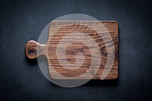 Handmade black walnut wood cutting board on the dark tabletop.