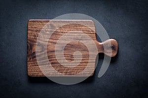 Handmade black walnut wood cutting board on the dark tabletop.