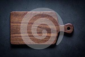 Handmade black walnut wood cutting board on the dark tabletop.