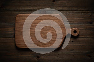 Handmade black walnut wooden chopping board on dark black wooden table.