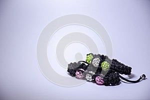 Handmade bracelets with green, pink and white beads and zircons on white background