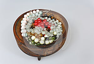 Handmade bracelets in a wooden bowl on an isolated white