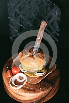 Handmade burger with beef, pickles, cheese and knife on wooden table. Top view