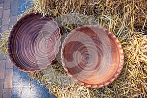 Handmade ceramic clay plates, decorated with carved circles, lie on a hay stack, Ukrainian traditional symbolic art